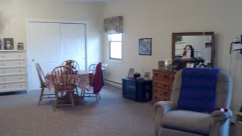 Spacious living room in Dolphin Manor with dining table, chairs, and recliner.