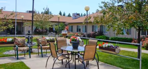 Outdoor courtyard with tables, chairs, planters, and a surrounding building.