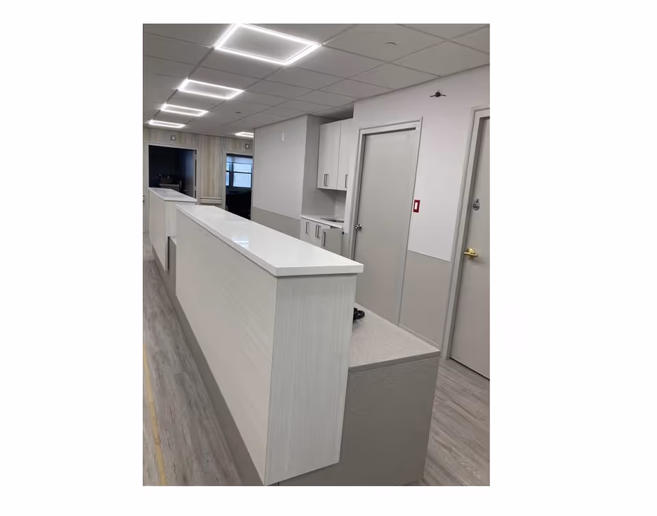 White reception desk along a hallway in a modern senior care facility.
