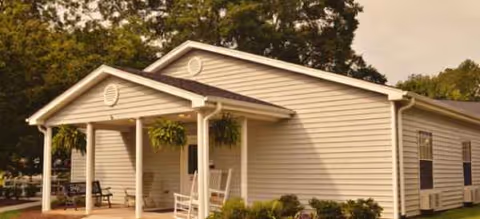 Single-story senior living facility with a covered front porch and rocking chairs.