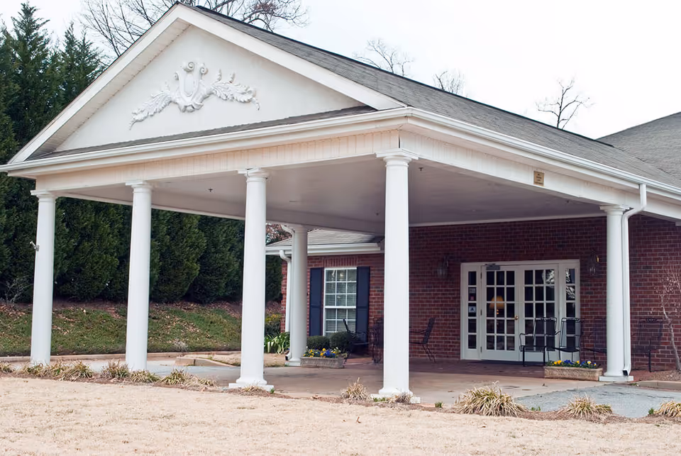 Covered brick entrance with a white columned portico and glass double doors.