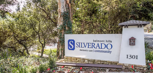 Entrance sign for Silverado Belmont Hills memory care community reading '1301' set among trees and flowers.