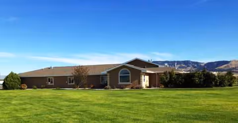Exterior view of Meadowlark Manor, a single-story senior living facility with a green lawn.