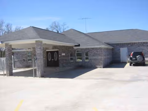 Brick senior living facility with a covered entrance, parking lot, and a parked SUV.
