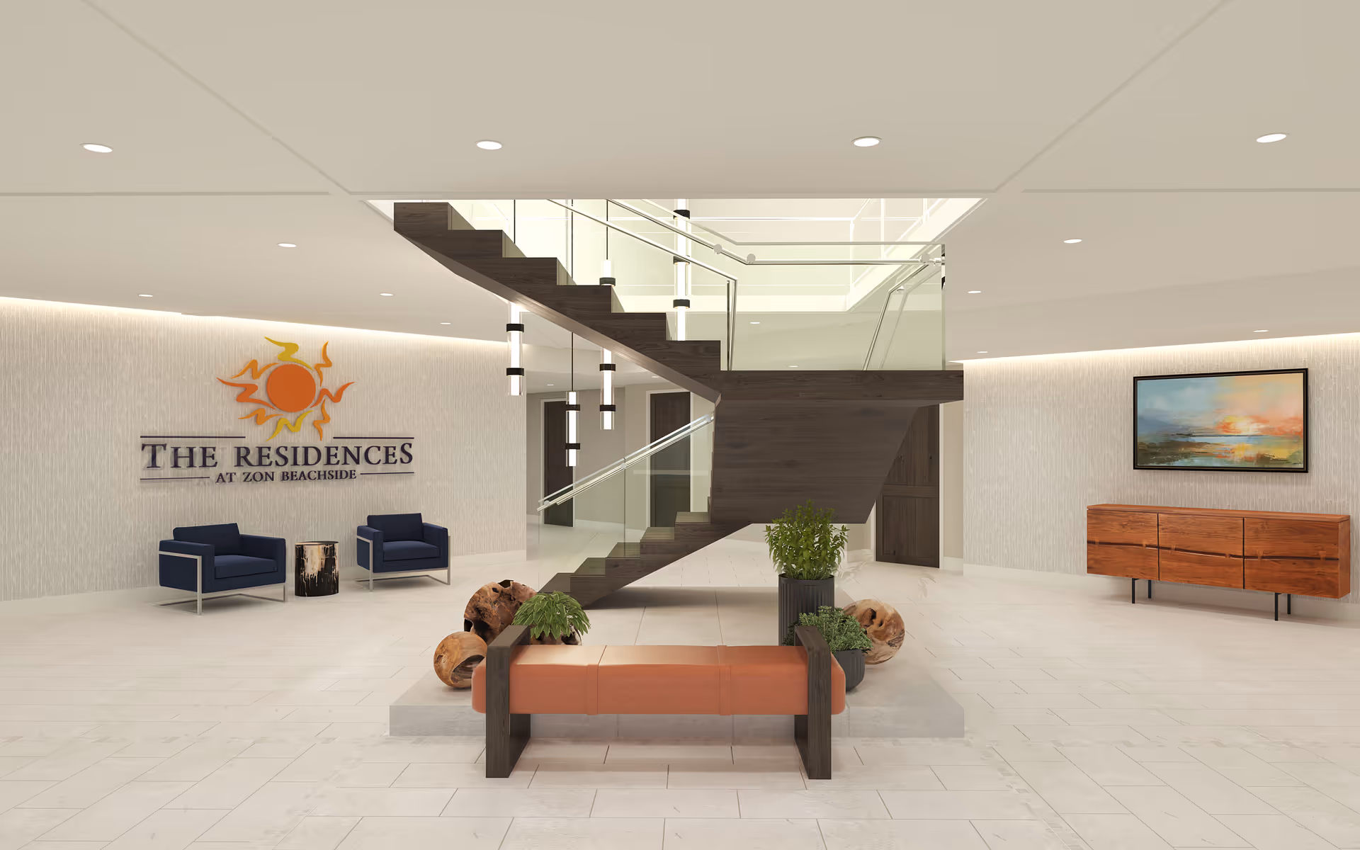 Modern interior lobby area of The Residences at Zon Beachside featuring a central staircase with glass railings, a bench with plants underneath, two blue armchairs with a small wooden side table, a wooden sideboard with a landscape painting above it, and the facility's logo on the wall.