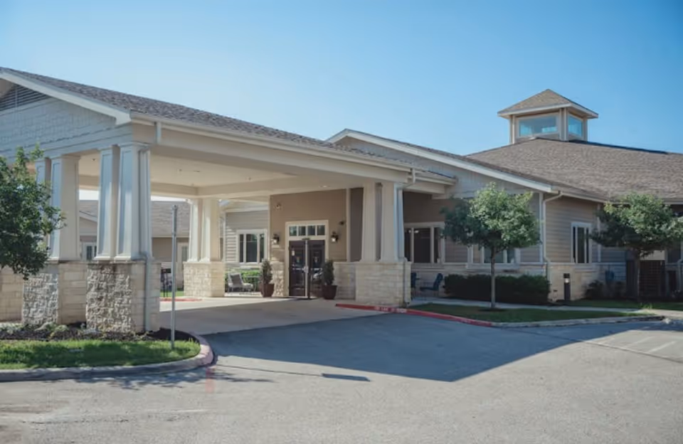 Exterior view of a senior living facility entrance with a covered driveway.