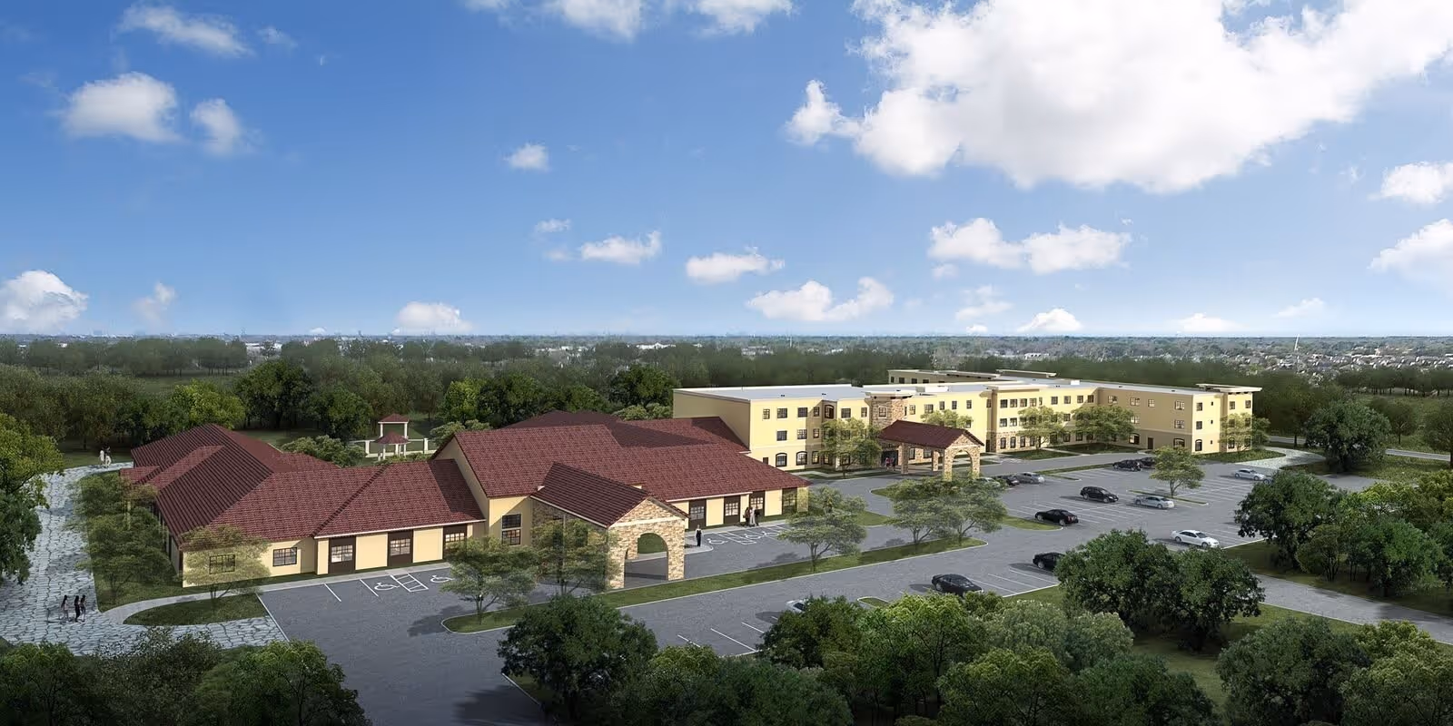 Aerial view of Laurel Glen at Sugar Land facility showing multiple connected buildings with red roofs and beige walls, surrounded by trees and greenery. There is a large parking lot with several cars parked, and a clear blue sky with scattered clouds above.
