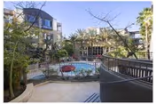 Courtyard with a swimming pool surrounded by palm trees and multi-story apartment balconies.