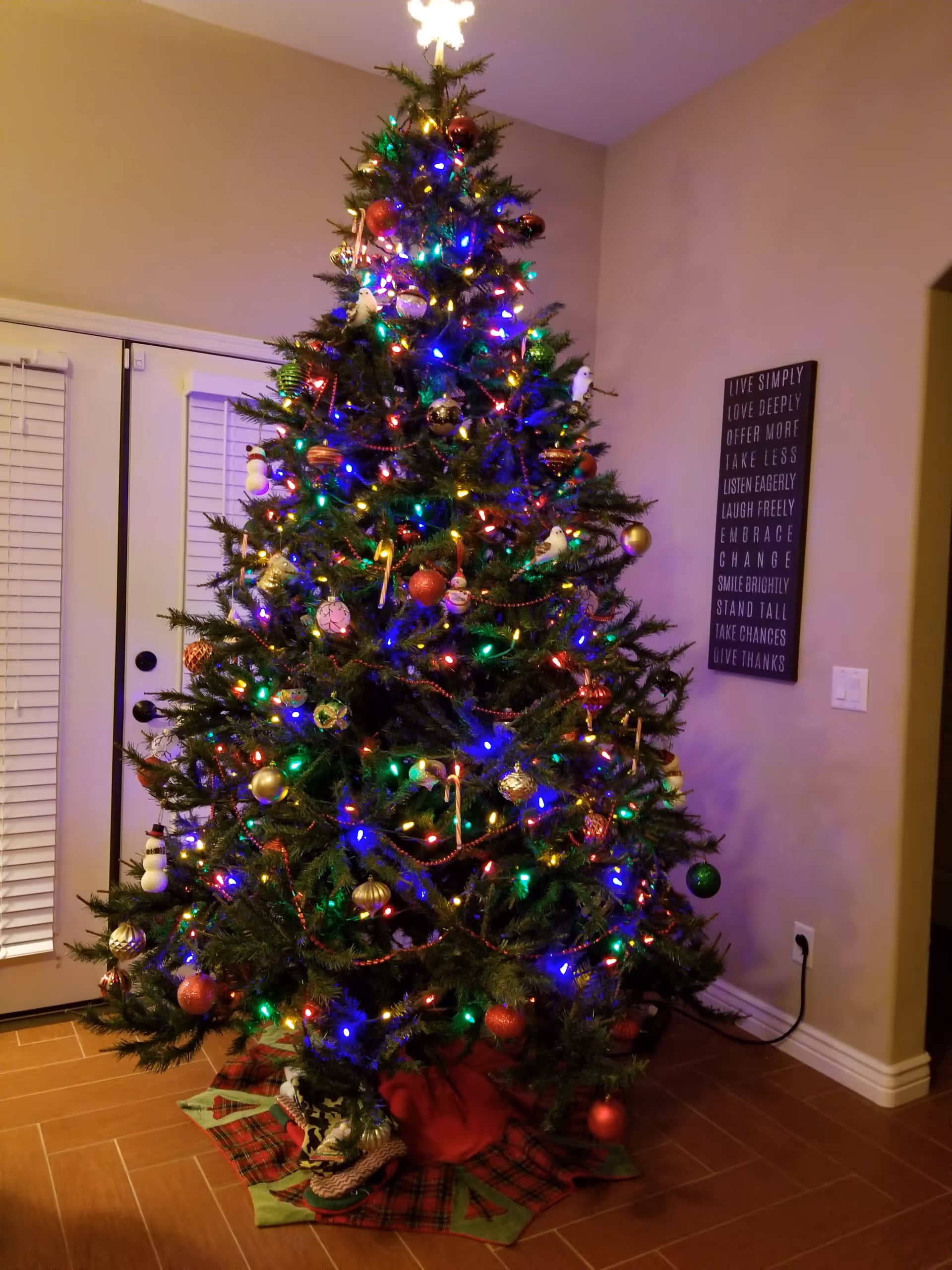 A decorated Christmas tree with colorful lights and ornaments standing in a living room corner.