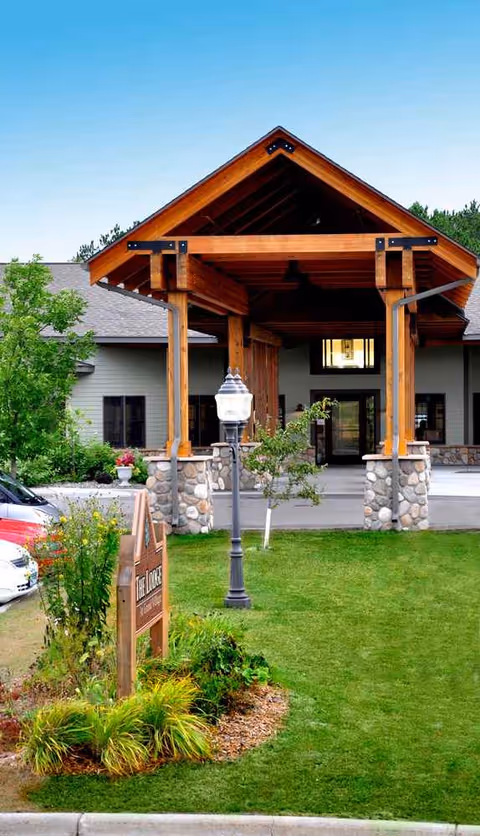Wooden entrance canopy with stone pillars at a senior living facility exterior.