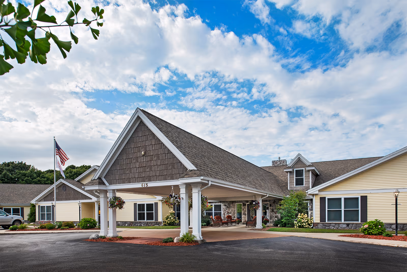 Exterior view of American House Charlevoix with a flag and lush landscaping.