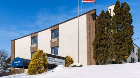 Regency at Jackson exterior building with flagpole, snow, and trees.