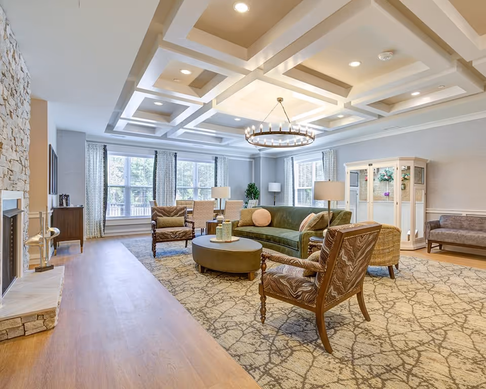 Spacious furnished living room with sofas, armchairs, chandelier, fireplace and large windows.