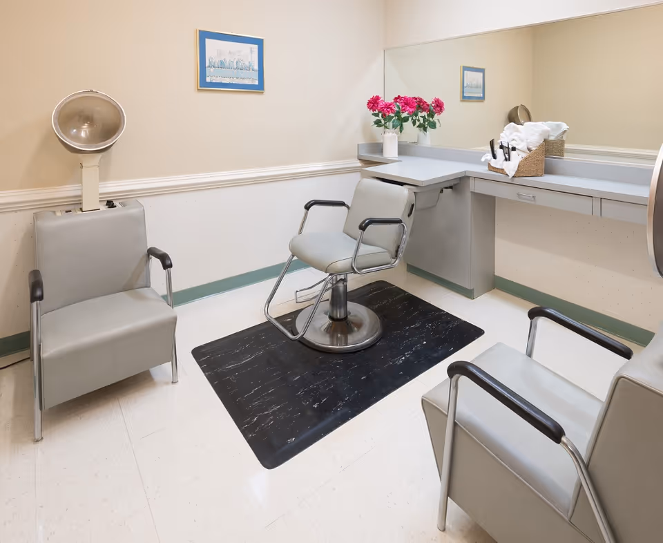 Hair salon interior at Green Leaf Care Center with chairs, a mirror, and flowers.