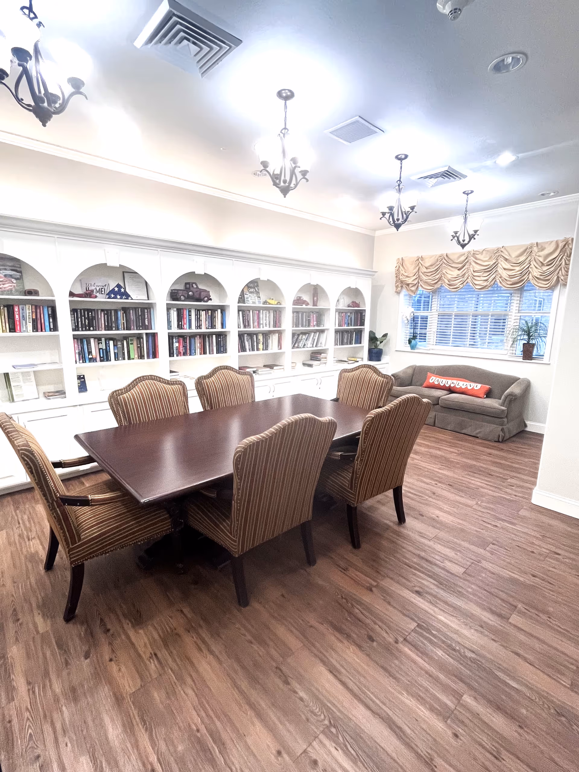 A spacious interior common room with a long table, bookshelves, and a sofa.