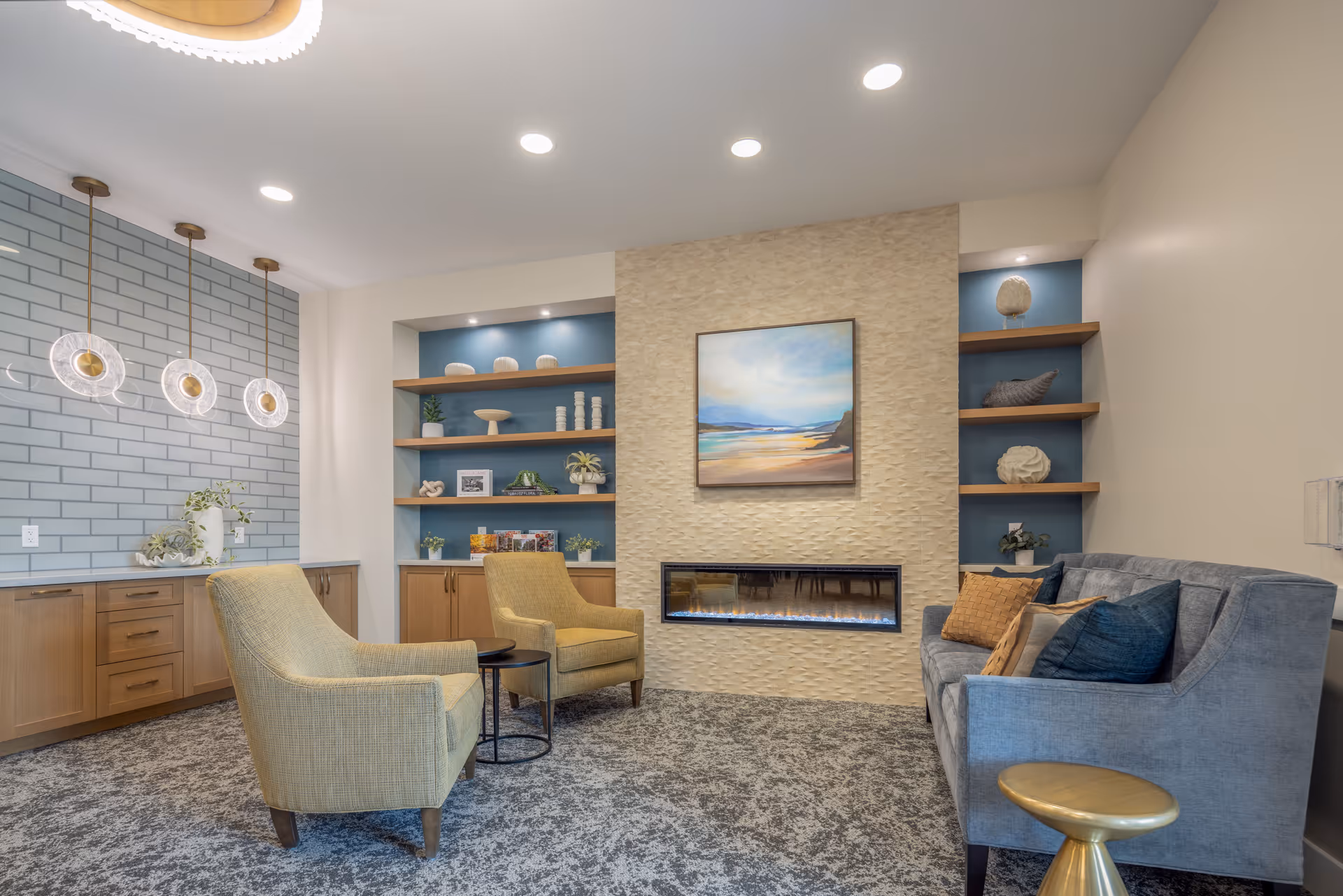 A modern lounge with two armchairs, a sofa, built-in shelving, a linear fireplace and pendant lighting.