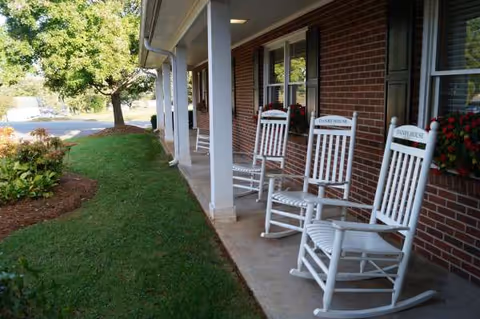 White rocking chairs labeled Danby House line a brick porch at the facility.