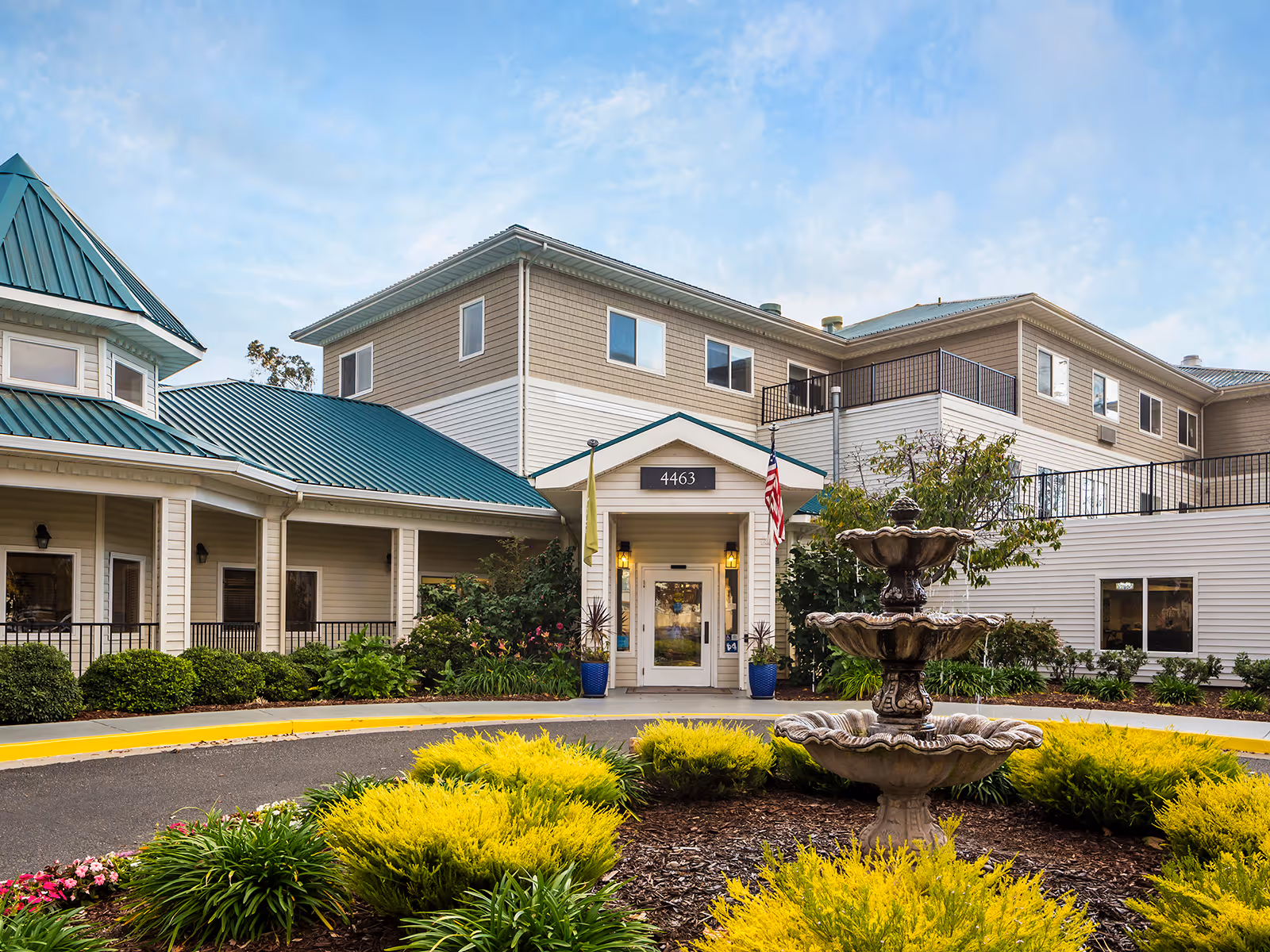 Exterior view of a senior living facility with fountain and landscaped entrance.