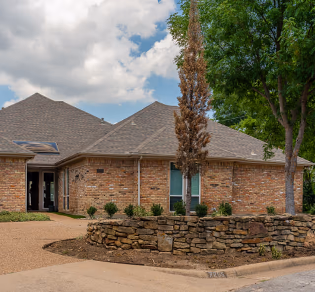 Brick senior living facility exterior with entrance and circular stone planter.
