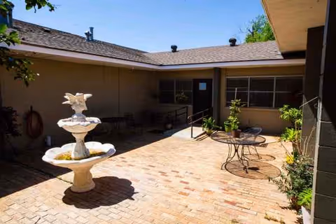 An outdoor courtyard at Lakeview Manor Nursing Home with a fountain, brick-paver patio, and seating.