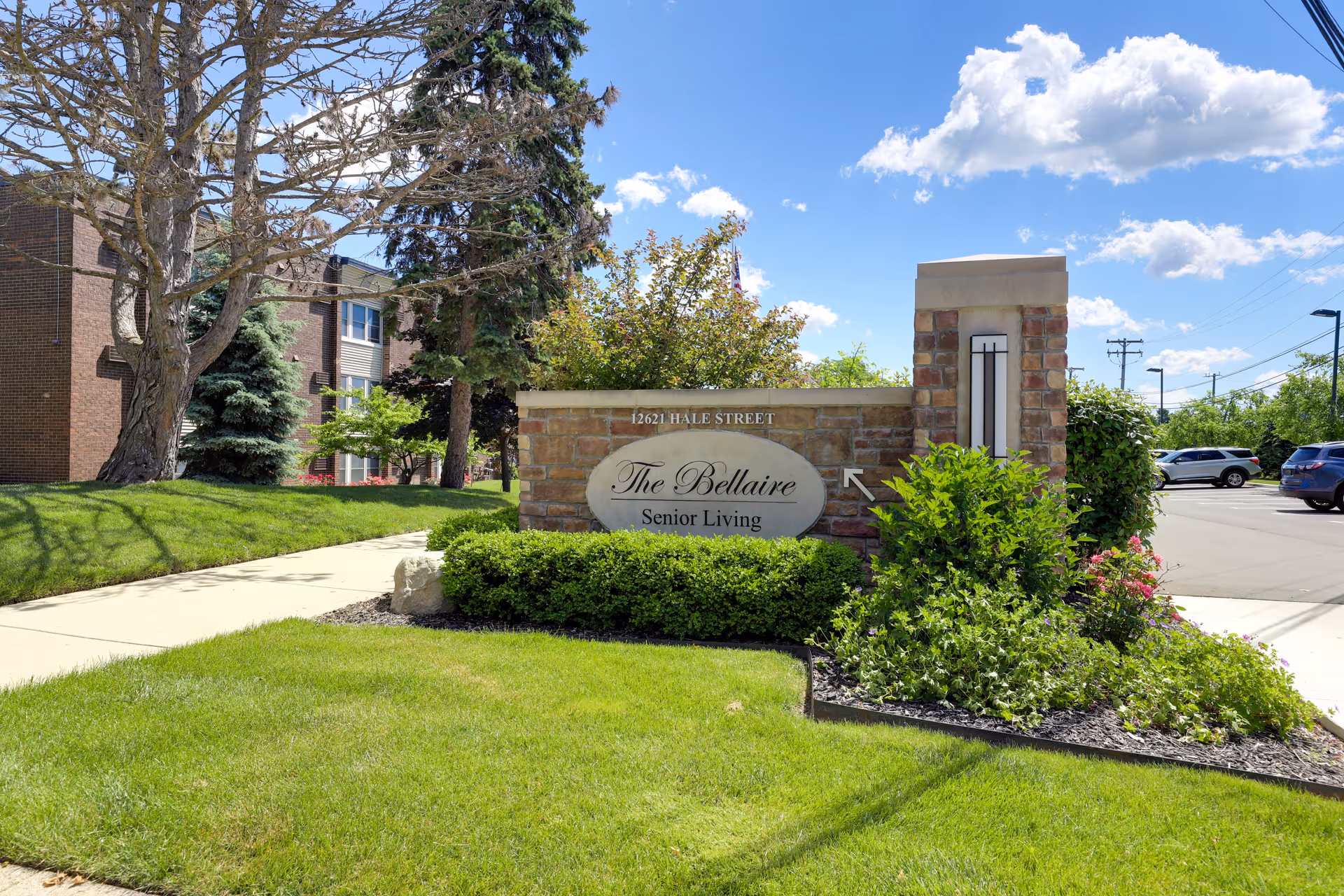 Stone sign reading The Bellaire Senior Living sits at the building entrance amid landscaping.
