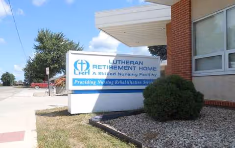Signage for Lutheran Retirement Home at the building exterior with shrubs nearby.