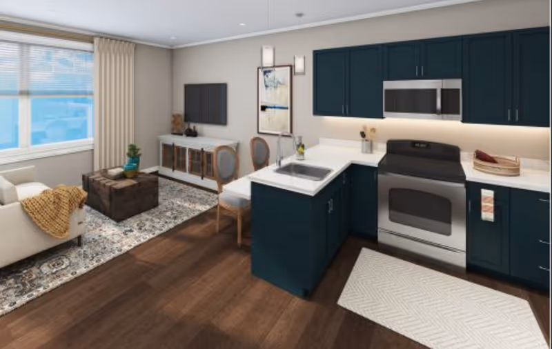 Open-concept living area and kitchen with dark teal cabinets, stainless appliances, a white sofa, rug, and wood floors.