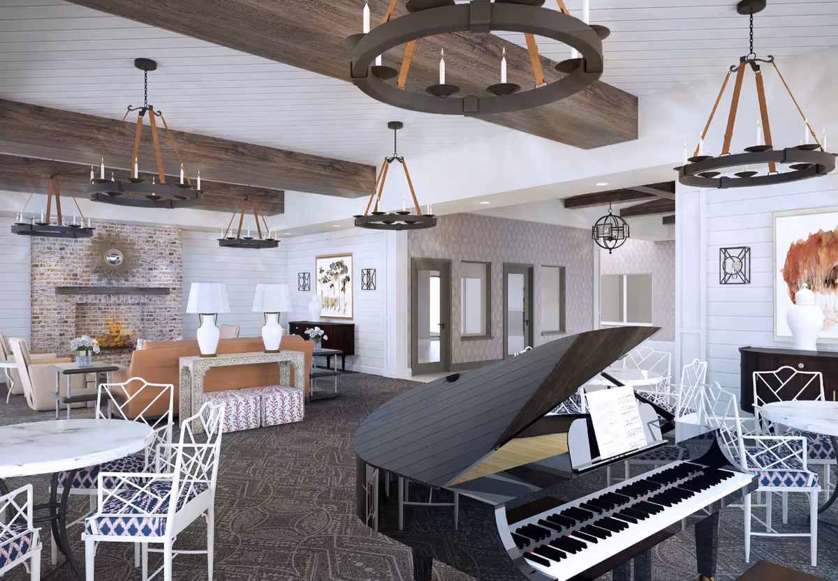 A spacious and elegant common area featuring a black grand piano with sheet music, several round tables with white chairs that have patterned cushions, a cozy seating area with beige sofas and armchairs near a brick fireplace, decorative wall art, and multiple rustic chandeliers hanging from a white ceiling with wooden beams.