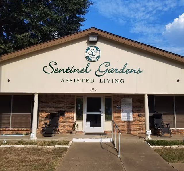 Front view of Sentinel Gardens Assisted Living building with sign and entrance stairs.