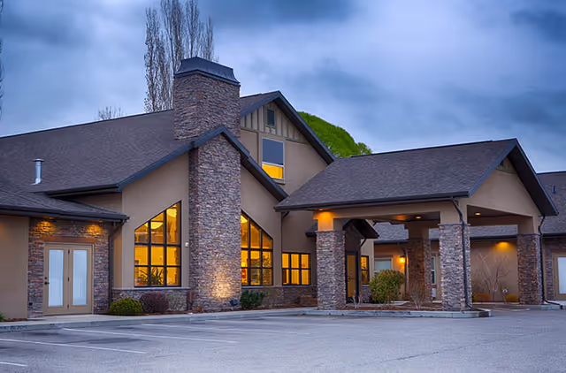 Stone-clad senior living facility exterior with a covered entrance and parking.