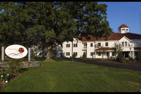 Sunnybrook Senior Living building front with trimmed lawn, trees, and a sign.