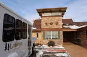Front entrance of Littleton Care and Rehabilitation showing a brick facade tower, the facility shuttle parked at the curb, and patches of snow.