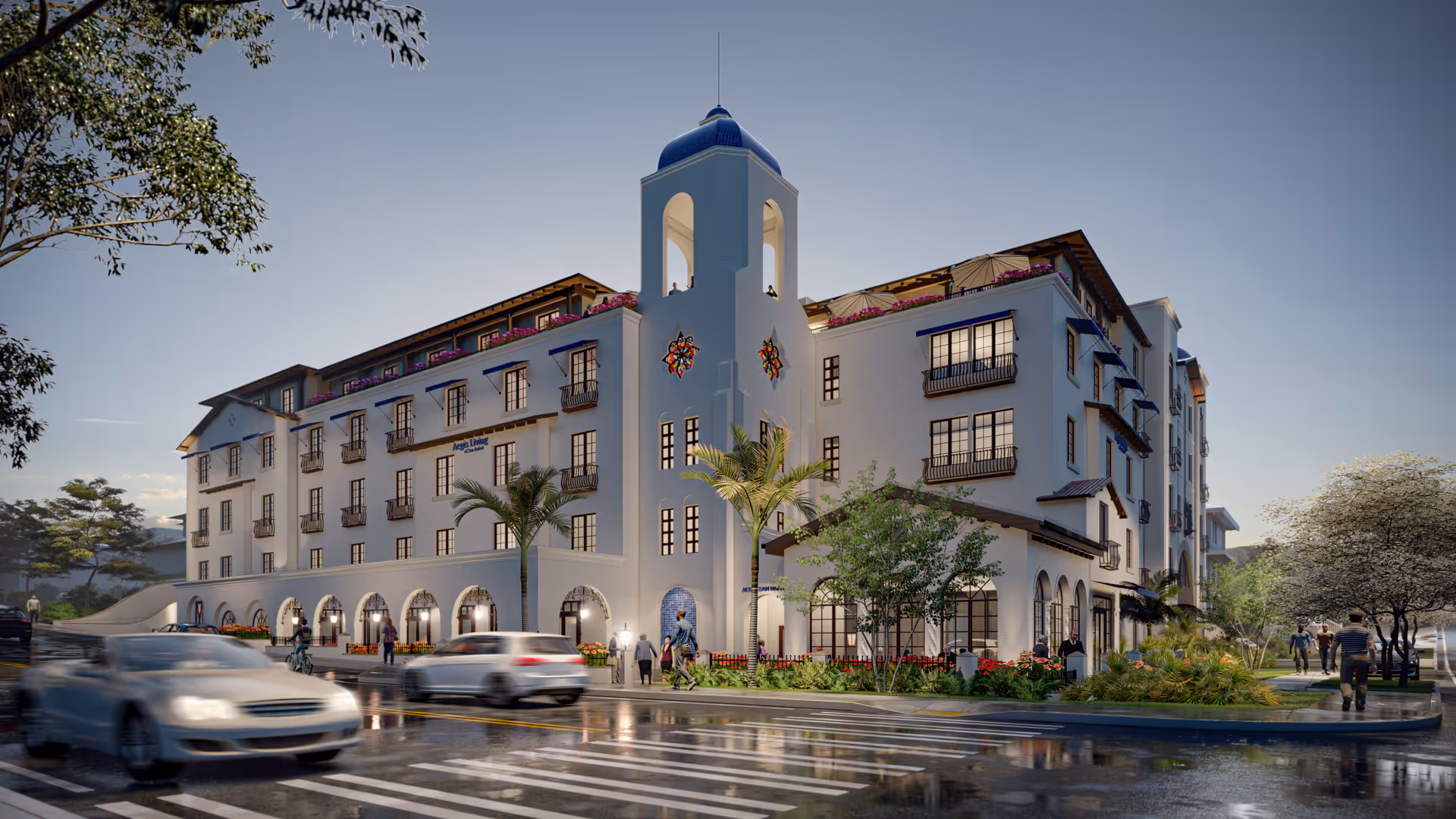 Exterior view of a large, multi-story senior living facility named Aegis Living San Rafael with Mediterranean architectural style, featuring white walls, arched windows and doorways, a blue dome tower, palm trees, and landscaped greenery. Several people are walking on the sidewalks and cars are driving on the wet street in front of the building during early evening.