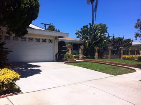 Front exterior of a single-story care facility with a garage, driveway, and landscaped yard.