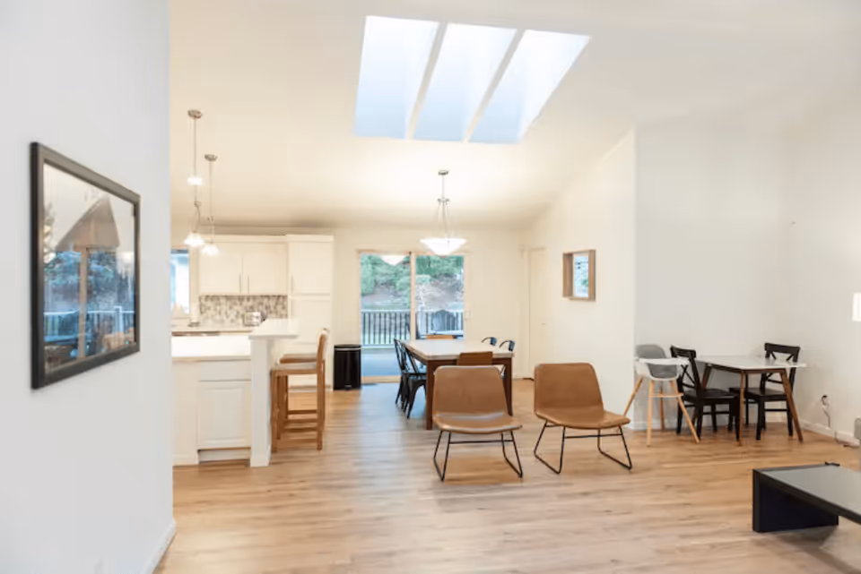 Open-plan living and dining area with skylights, a kitchen island, dining table, and several chairs.