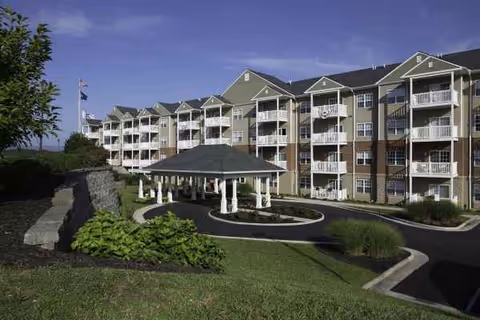 A multi-story senior living facility with balconies and a central gazebo at the entrance.