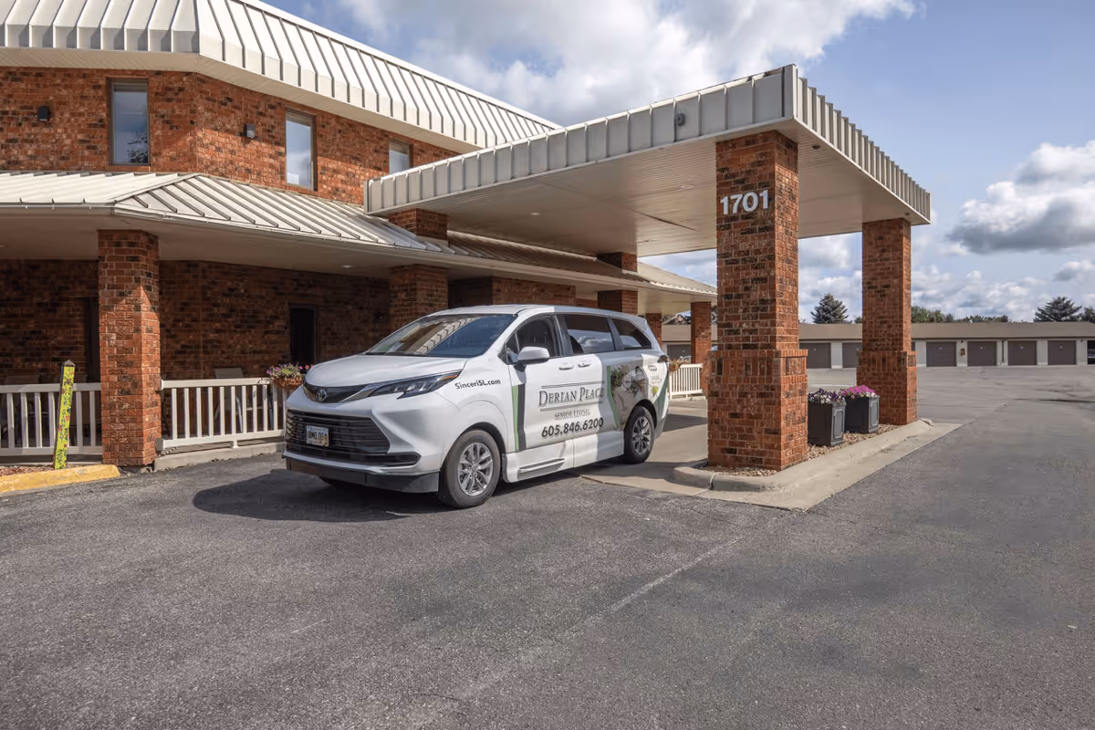 Exterior view of Derian Lodge with a white van parked at the entrance, featuring a brick facade and a covered entryway.