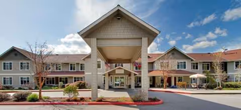Exterior view of Brookdale Montclair Poulsbo front entrance with a covered drop-off and surrounding buildings.