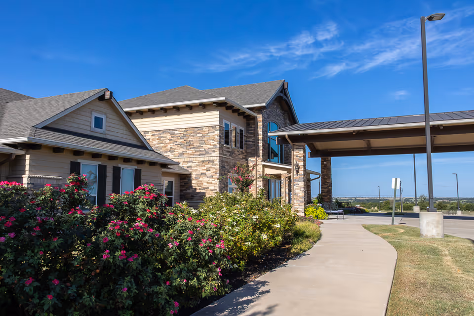 Exterior view of Bristol Park at Cleburne Assisted Living with stone facade and landscaped entrance.