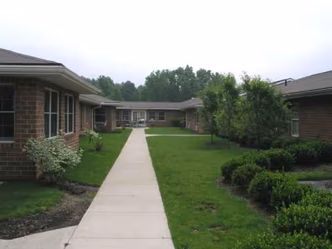 A concrete walkway runs between brick Altercare Wadsworth buildings with green lawns and shrubs.