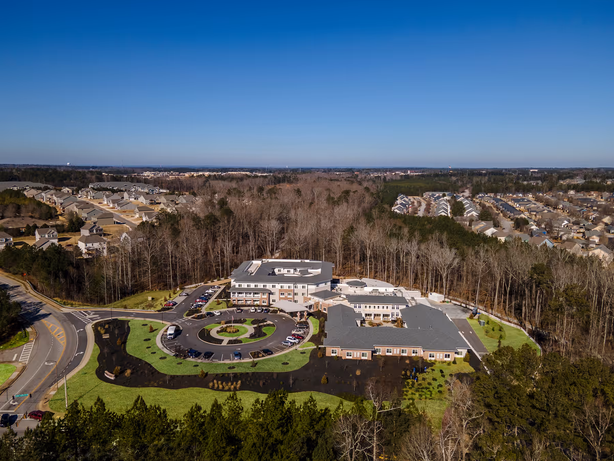 Aerial view of a senior living campus with circular drive, parking, and surrounding woods.