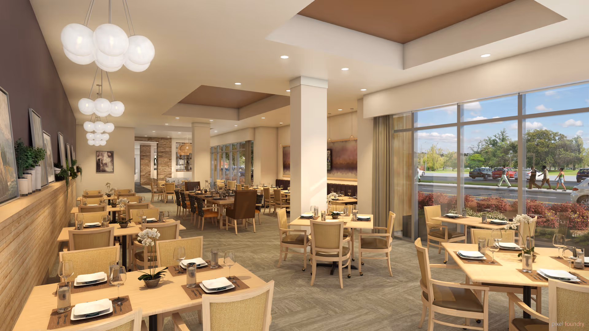 A spacious and well-lit dining room with multiple wooden tables and chairs arranged neatly. Each table is set with plates, glasses, and cutlery, and decorated with small flower arrangements. Large windows on one side allow natural light to fill the room, showing a view of a parking lot and people walking outside. Modern pendant lights hang from the ceiling, and artwork and plants decorate the walls.