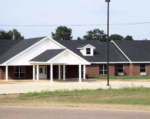 Exterior view of a brick senior living center with a white covered entrance.