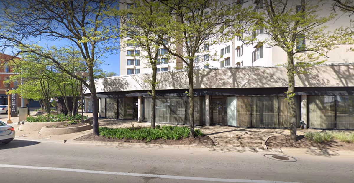 Street view of the Luther Center building exterior with trees and landscaping in front, large windows, and a multi-story structure behind.