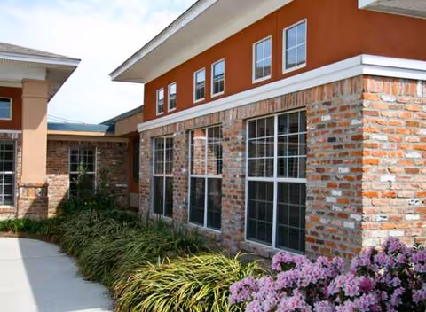 Exterior view of Belle Teche Nursing and Rehabilitation Center with brick facade, windows, and landscaping.