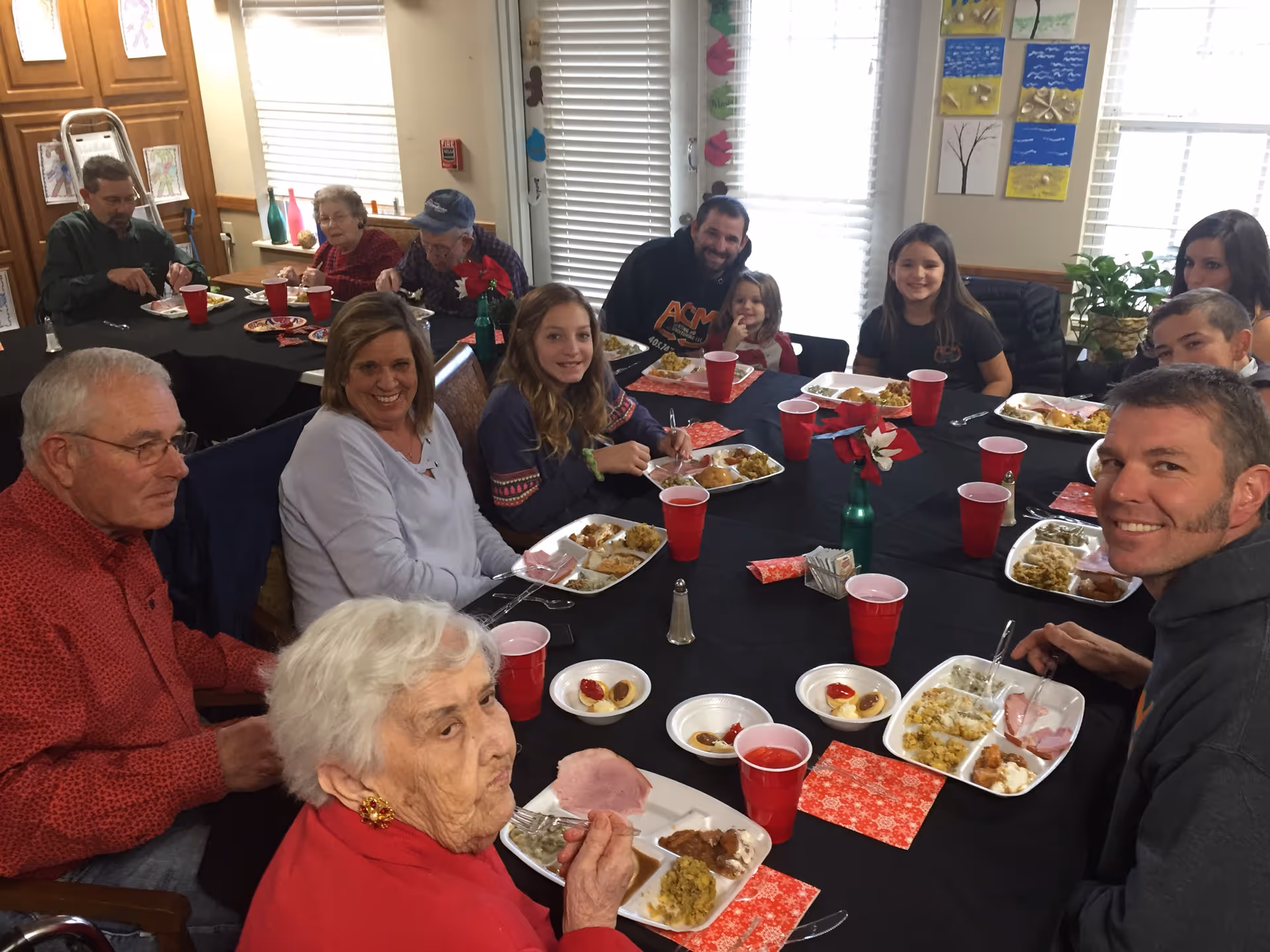 A group of seniors and family members seated around a table eating a meal in a dining room.