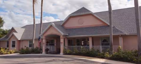 Single-story memory care facility with a pink exterior and covered front entrance.
