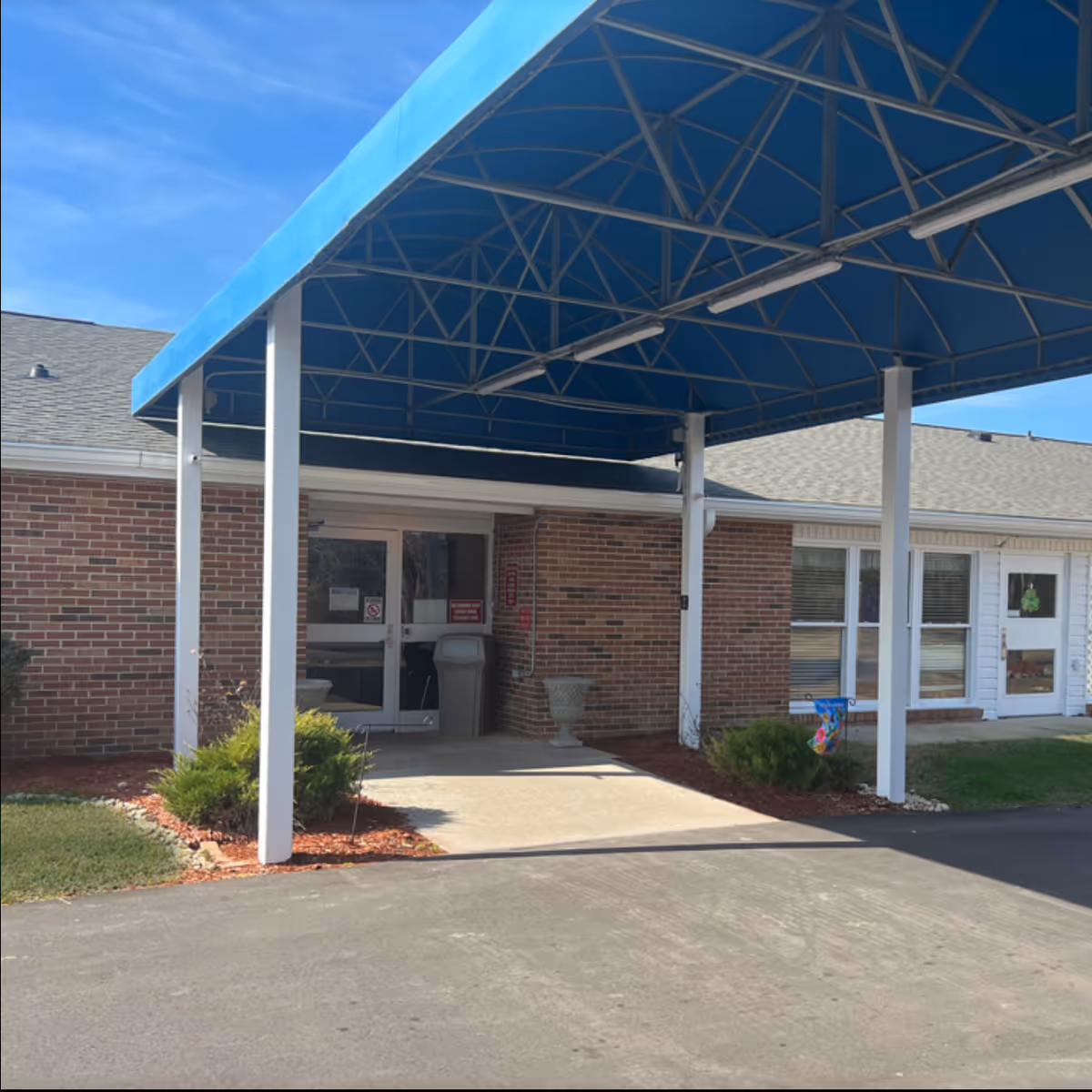 Exterior view of Windsor Rehabilitation and Healthcare Center entrance with a blue canopy.