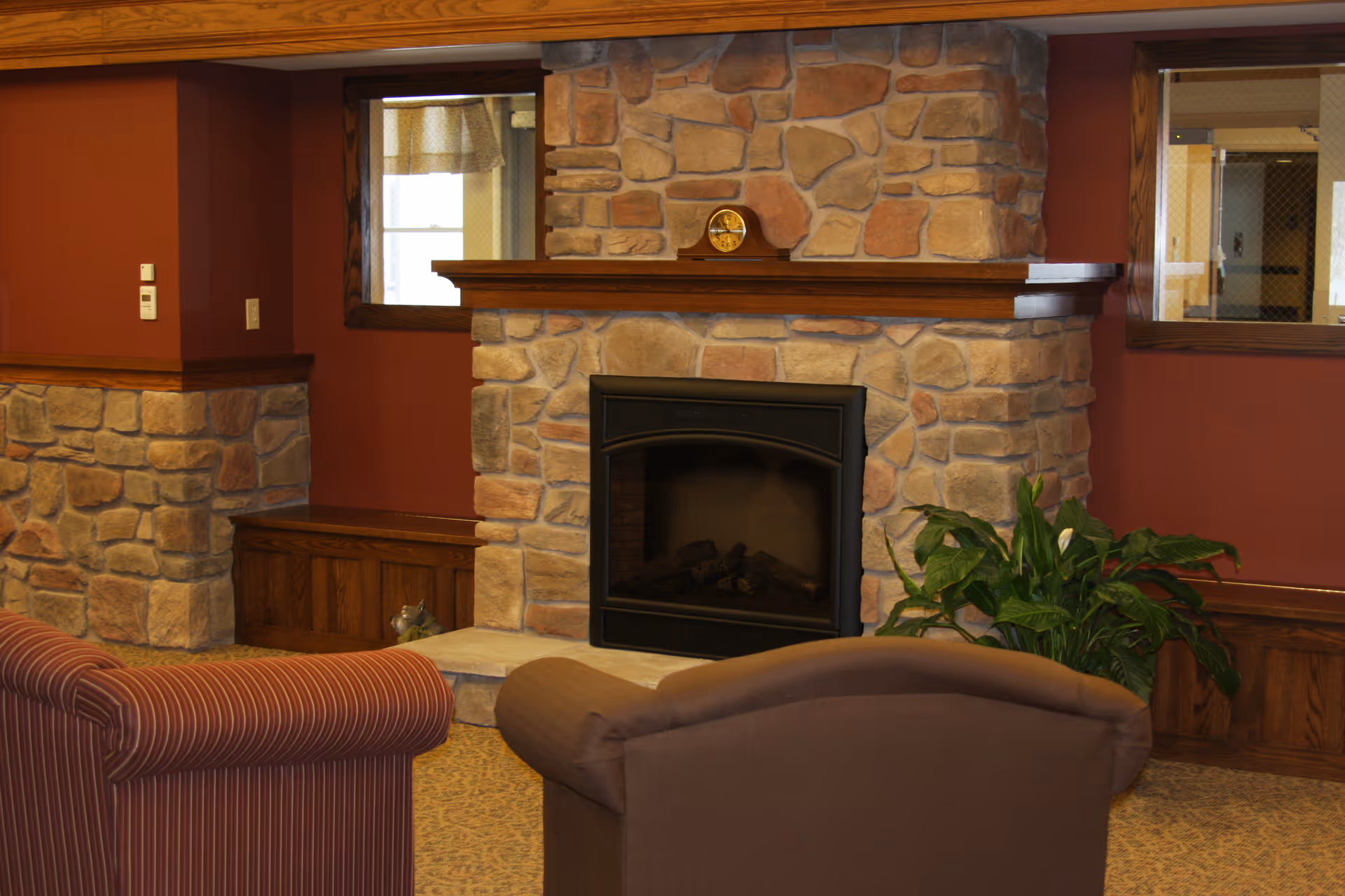 Cozy lounge area featuring a stone fireplace, two upholstered chairs, and a potted plant.