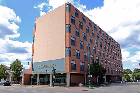 Exterior view of Honey Creek Heights Senior Living, a brick, multi-story building at a street corner.